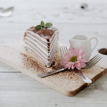 delicious piece of cake and flower on wooden table